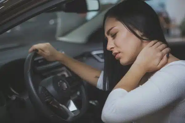 Female driver holds her neck in pain after car accident