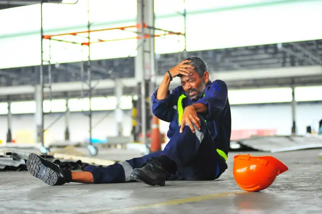A worker on the floor, holding his head after a work related accident.