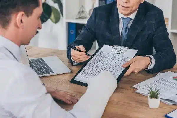 A person signing documents with a lawyer.