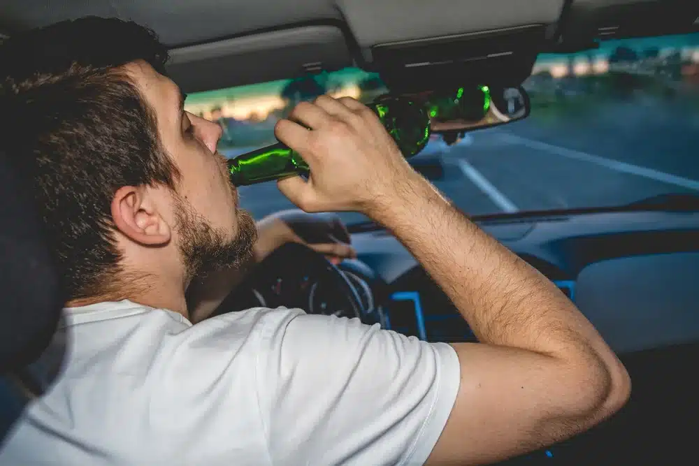 A man drinking beer and driving.