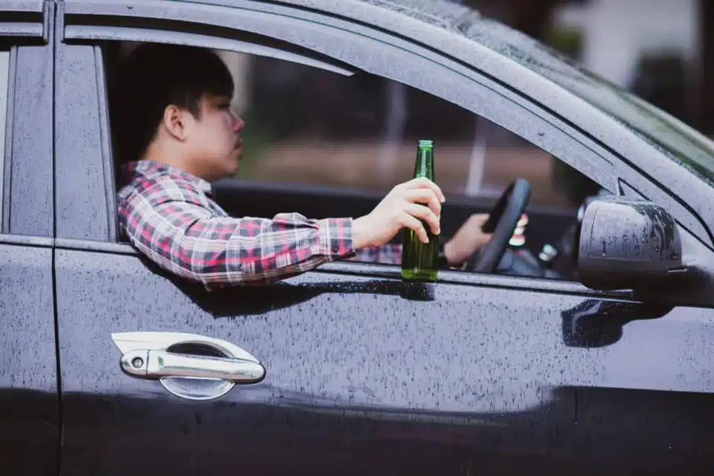 Person driving while holding an alcoholic beverage.