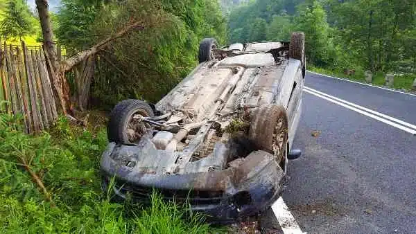 A rolled over car on the side of a road.