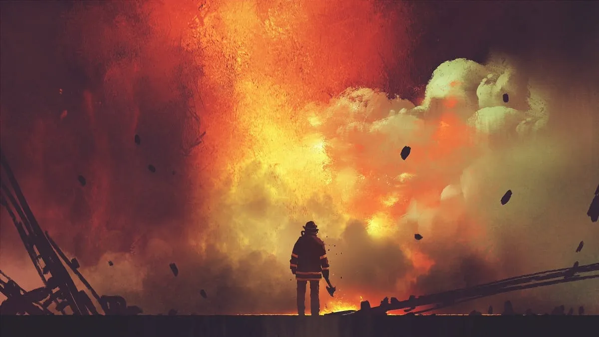 A firefighter in front of an explosion.