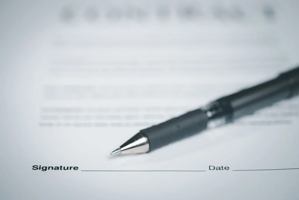 A document with a blank signature sign and a black pen sitting on top.