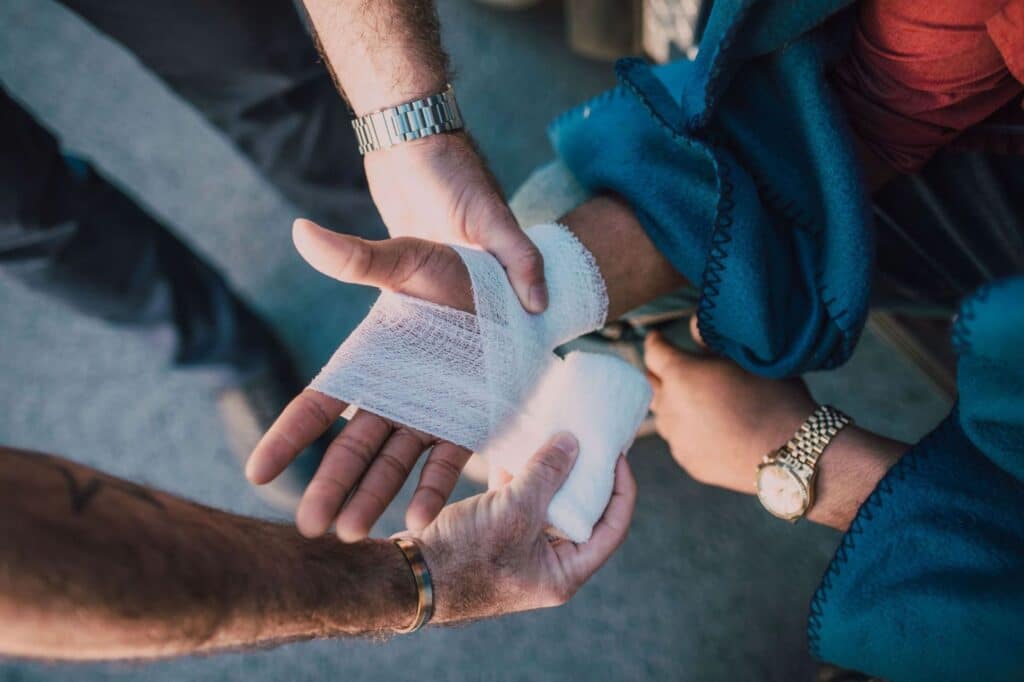 A hand being wrapped with gauze by someone else.