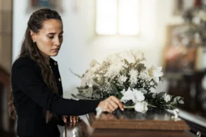 A woman placing a flower on top of a casket.