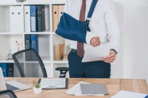 A person with a broken arm in a sling trying to work.