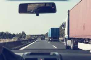 A car driving next to a truck on a highway.