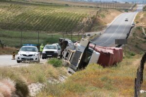 A truck accident scene with a truck rolled over.