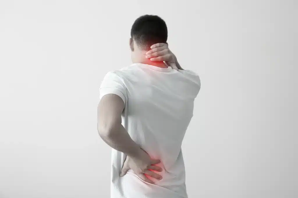 A person holding their neck and back in pain.