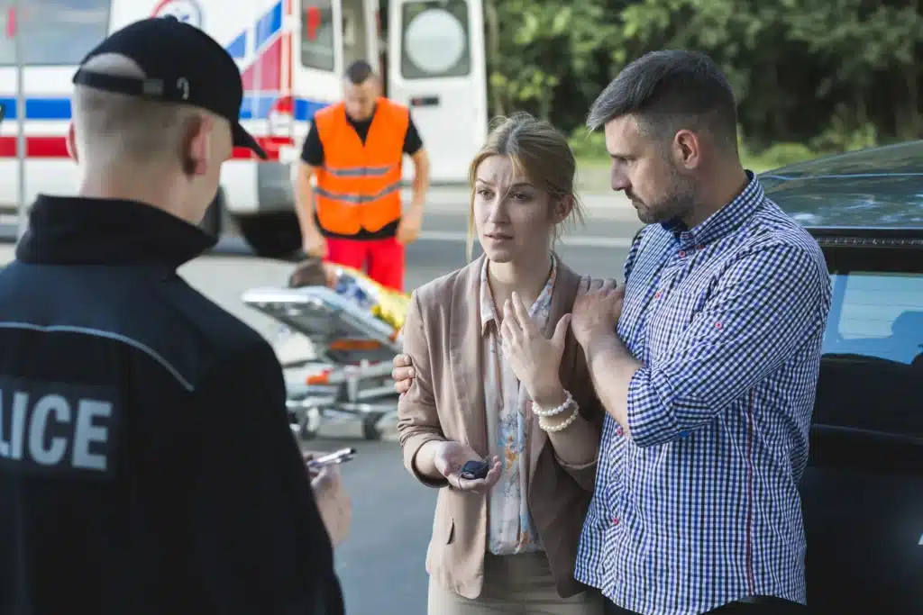 Two adults talking to the police at Houston car accident scene. 