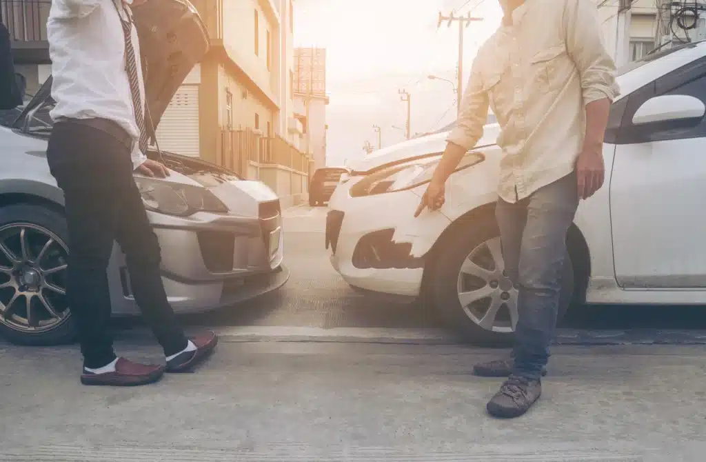 Two men examining vehicle damage after a crash, highlighting issues that may lead to uninsured motorist claims in Houston.